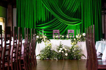 Elegant wedding reception setup with green drapes and floral decor.の写真素材