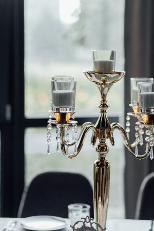 Elegant gold candelabra with crystal accents on dining table setting.の写真素材
