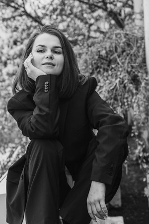 Young caucasian female in suit sitting outdoors in thoughtful pose.の写真素材