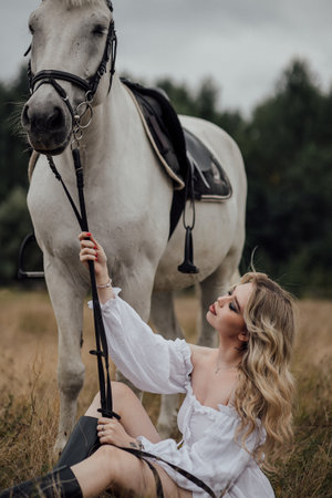 Young caucasian female with white horse in countryside setting.の写真素材