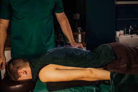 Male receiving back treatment massage therapy session wellness relaxation.の写真素材