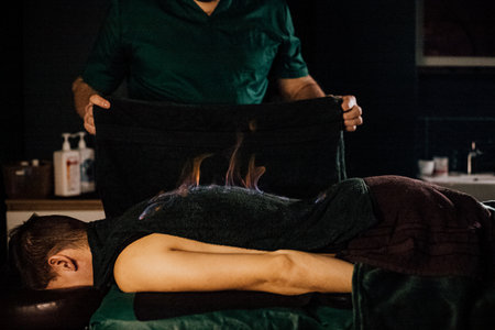 Male receiving fire therapy on back in spa setting.の写真素材