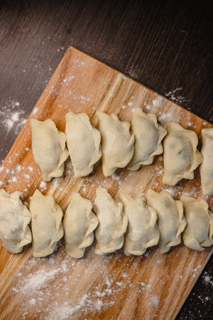 Homemade fresh dumplings on wooden board with flour dusting.