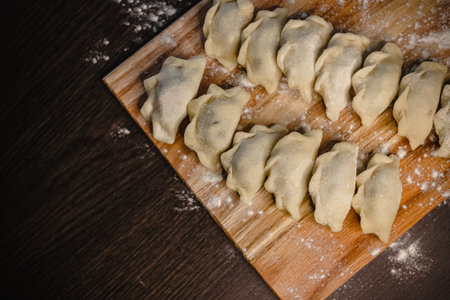 Fresh homemade dumplings on wooden board with flour dusting.の写真素材