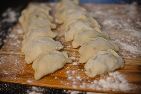 Freshly made homemade dumplings on wooden board with flour dusting.の写真素材