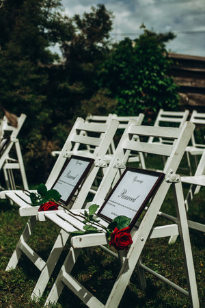 Outdoor wedding ceremony chairs with reserved signs and red roses.の写真素材
