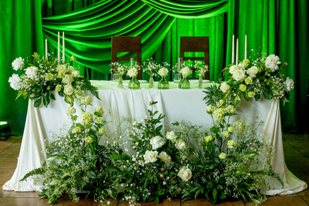 Elegant wedding reception setup with green drapes and white floral decorations.の写真素材