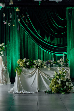 Elegant wedding reception table with green drapes and floral decor.の写真素材