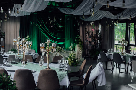 Elegant wedding reception hall with candles and green velvet drapes.の写真素材