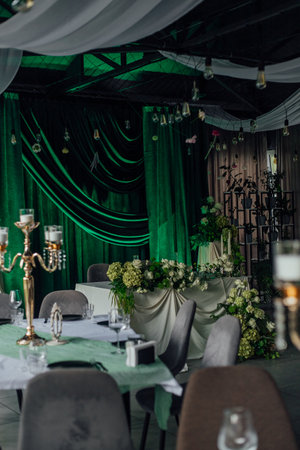 Elegant banquet hall with green velvet drapes and floral decor.の写真素材