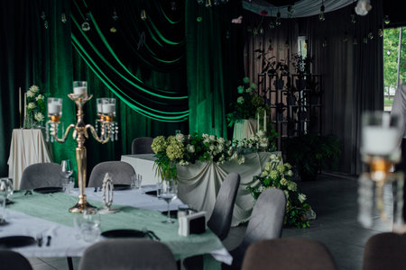 Elegant wedding reception with green velvet drapes and white floral arrangements.の写真素材