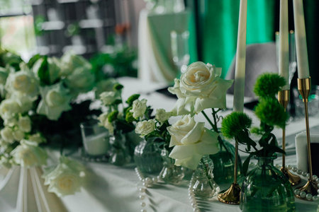 Elegant wedding table decor with white roses and candles in luxurious setting.の写真素材