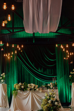 Elegant indoor wedding venue with draped ceiling and green velvet curtains.の写真素材