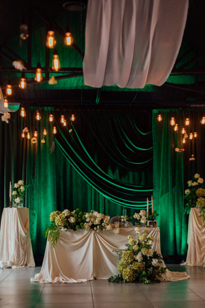 Elegant wedding reception venue with green velvet curtains and floral decorations.の写真素材