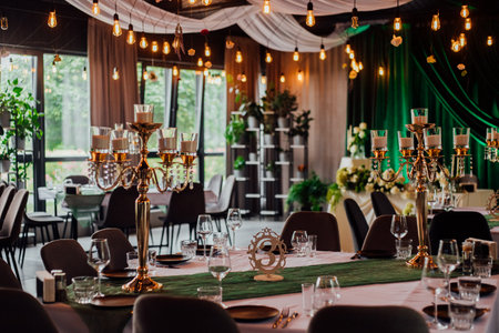 Elegant wedding reception with candleholders and green accents in decorated banquet hall.の写真素材