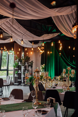 Elegant wedding reception venue with candles and green drapes.の写真素材