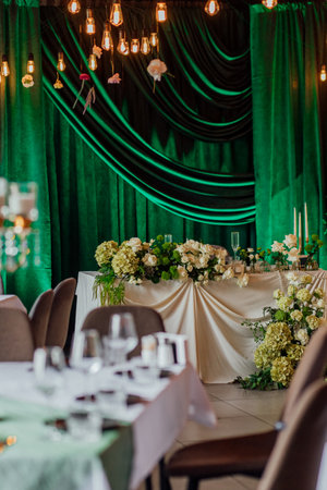 Elegant wedding reception with green drapes and floral centerpieces.の写真素材