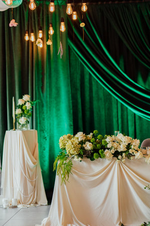 Elegant wedding table with greenery and hanging lights in luxurious setting.の写真素材