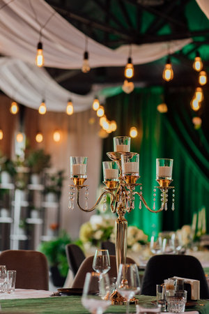 Elegant indoor event with gold candle holder and ambient string lights.の写真素材