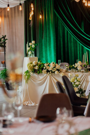 Elegant wedding reception table with green drapes and white floral arrangements.の写真素材