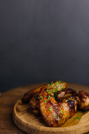 Delicious grilled chicken wings on wooden platter.