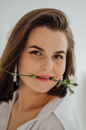Caucasian young female with flower and pearl earrings smiling elegantly.の写真素材