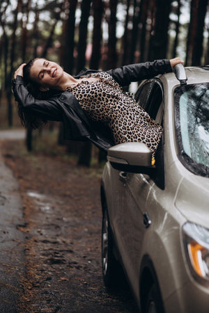 Woman in leopard dress enjoying nature with the car window down in a forest.の写真素材