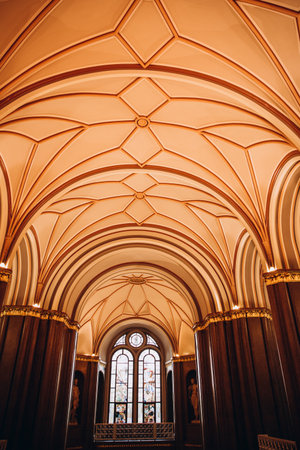 Majestic cathedral interior with ornate vaulted ceiling and stained glass window.の写真素材