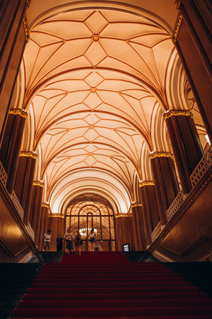 Grand architectural interior with ornate ceilings and red carpet staircase leading to a majestic hall.の写真素材