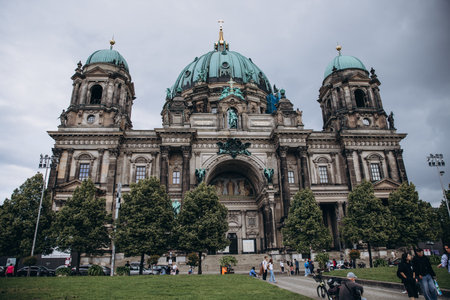 Historic architecture of the Berlin Cathedral on a cloudy day with a vibrant city atmosphere.の写真素材
