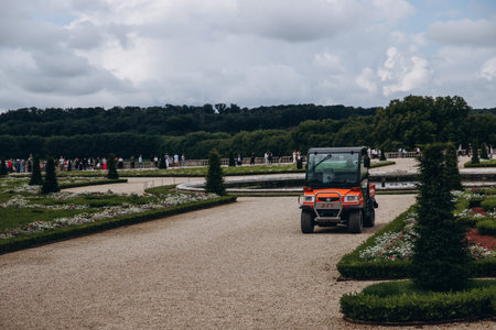 Gardening vehicle on a gravel path surrounded by lush greenery and trees
