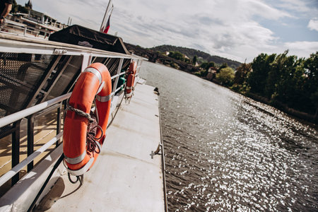 Lifesaver ring on a cruise ship deck overlooking a scenic river landscape