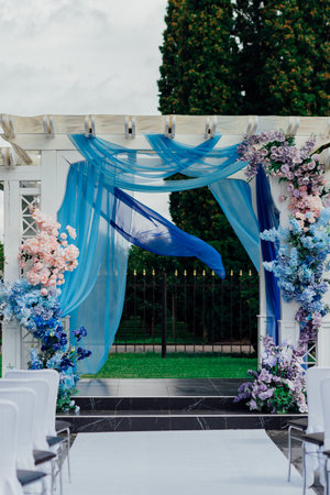 Elegant wedding arch decorated with blue and pink floral arrangements in an outdoor setting.の写真素材