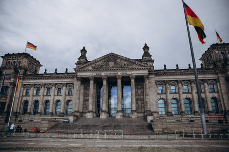 Majestic view of the historic Reichstag building in Berlin with German flags waving.の写真素材