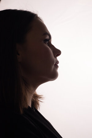 Elegant side profile of a woman against a bright background.の写真素材