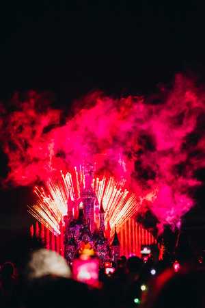 Nighttime fireworks display over a magical castle with vibrant pyrotechnics and bright lights.