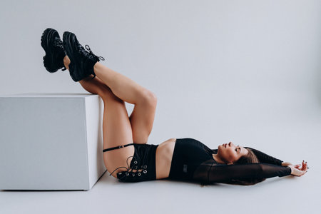 young woman in black lingerie lying on cube isolated on greyの写真素材