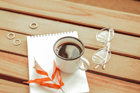 Cup of coffee with notebook on wooden backgroundの写真素材