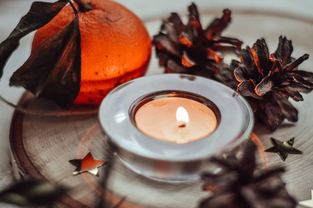 burning candle surrounded by pine cones and tangerinesの写真素材