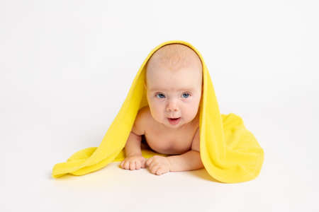 baby girl in a towel after bathing on a white isolated background looks at the camera, baby 3-6 months, space for textの写真素材