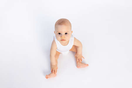 cute baby boy in a white bodysuit on a white isolated background looks at the camera, baby 8 months, space for textの写真素材