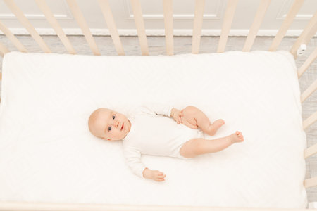 Sleeping baby and his toy in white crib. Nursery interior and bedding for kids. Cute little boy napping in bassinet. Kid taking a nap in white bedroom. Healthy child in bodysuit pajamas.の写真素材