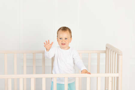 baby 2 years old is sitting in the crib and waiting for his mother.の写真素材