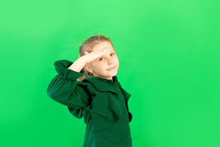 a 6-7-year-old girl on a green isolated background looks into the distance, a place for textの写真素材