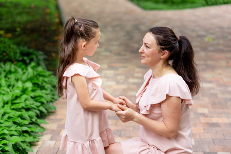 Happy mother and daughter 5-6 years old walk in the Park in the summer, mother talks to her...