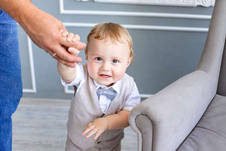 dad holds baby son 1 year old by the hand in a photo Studio on a gray background, family day, fathers dayの写真素材