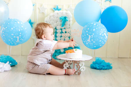 baby boy 1 year in a photo Studio with a cake and balloons, Birthday of a child 1 year, baby eats cakeの写真素材