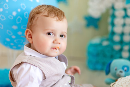 baby boy 1 year in a photo Studio with a cake and balloons, Birthday of a child 1 year, baby eats...