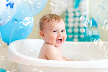 baby boy celebrates birthday 1 year in a bath with balloons, bathing baby with blue balloonsの写真素材
