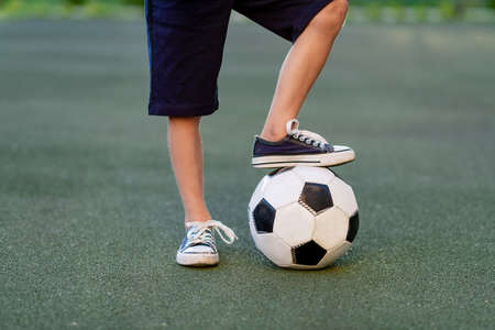 feet of a child boy with a soccer ball on a green lawn on a football field, sports section, trainingの写真素材